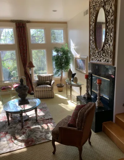 A living room with large windows and a fireplace.