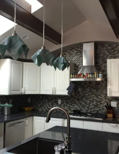 A kitchen with black counter tops and a skylight.