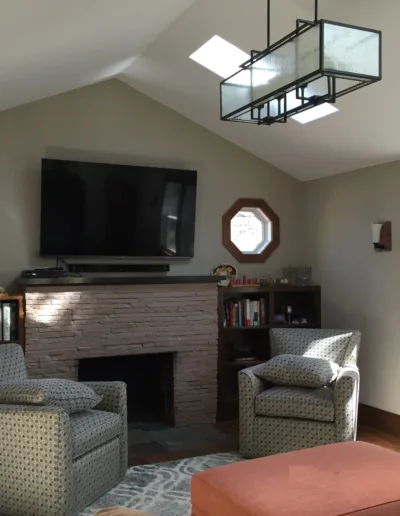 A living room with a fireplace, chairs and a tv.